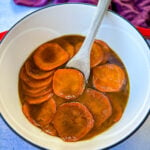 stovetop Southern soul food candied sweet potatoes yams in a Dutch oven with a wooden spoon