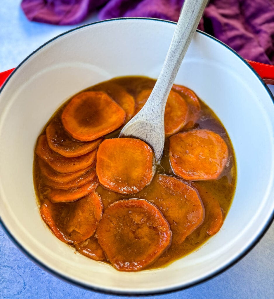 stovetop Southern soul food candied sweet potatoes yams in a Dutch oven with a wooden spoon