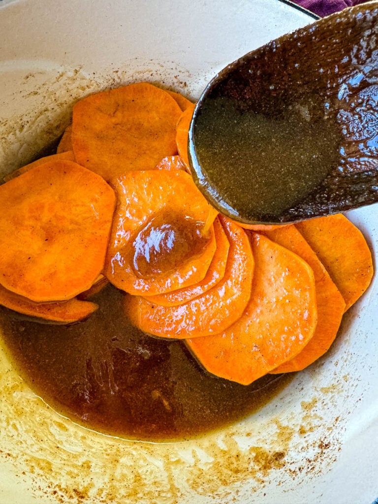 stovetop Southern soul food candied sweet potatoes yams in a Dutch oven with a wooden spoon