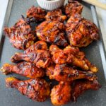 grilled bbq chicken thighs and drumsticks on a sheet pan with bbq sauce