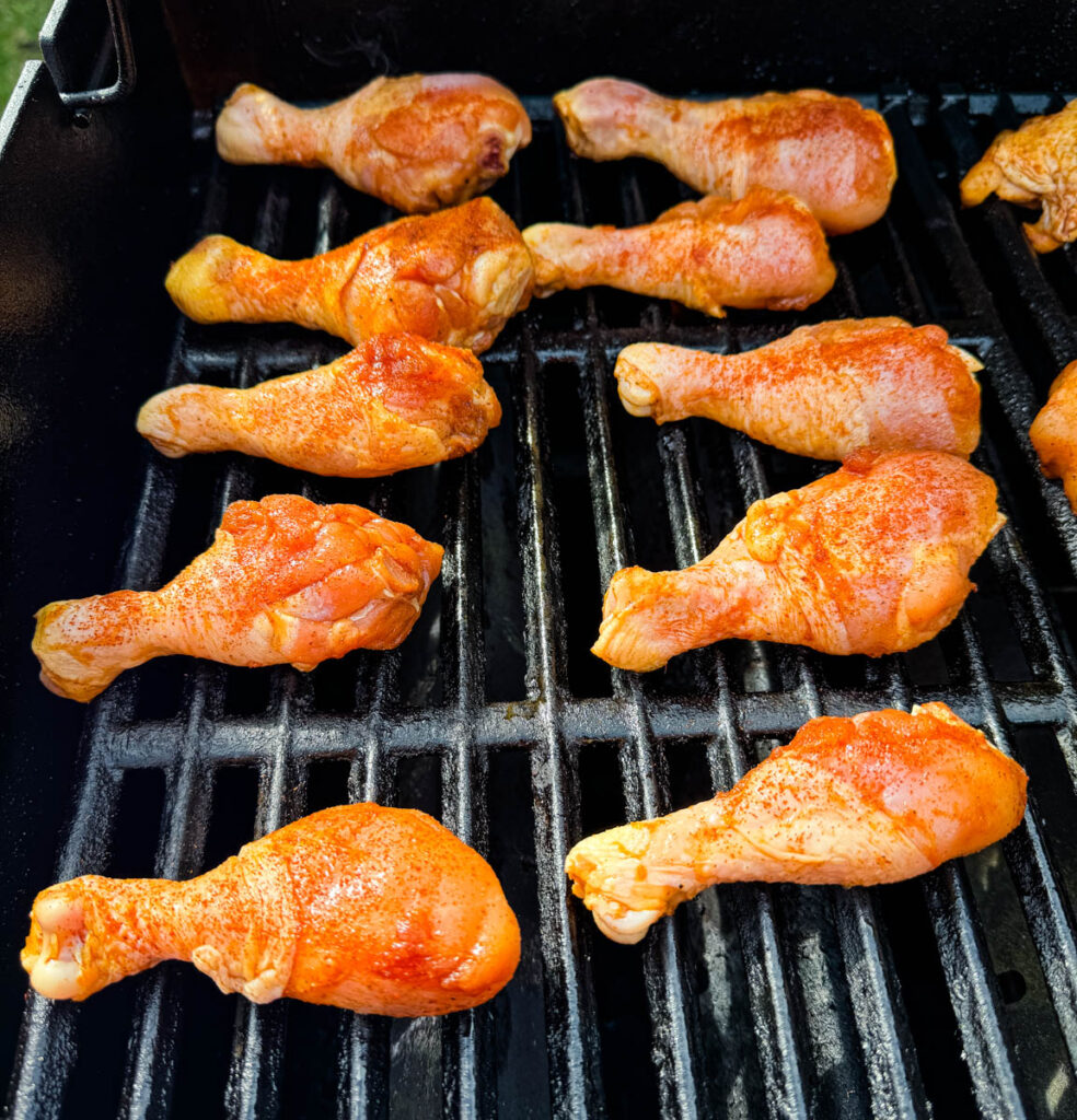 raw seasoned chicken drumsticks on grill