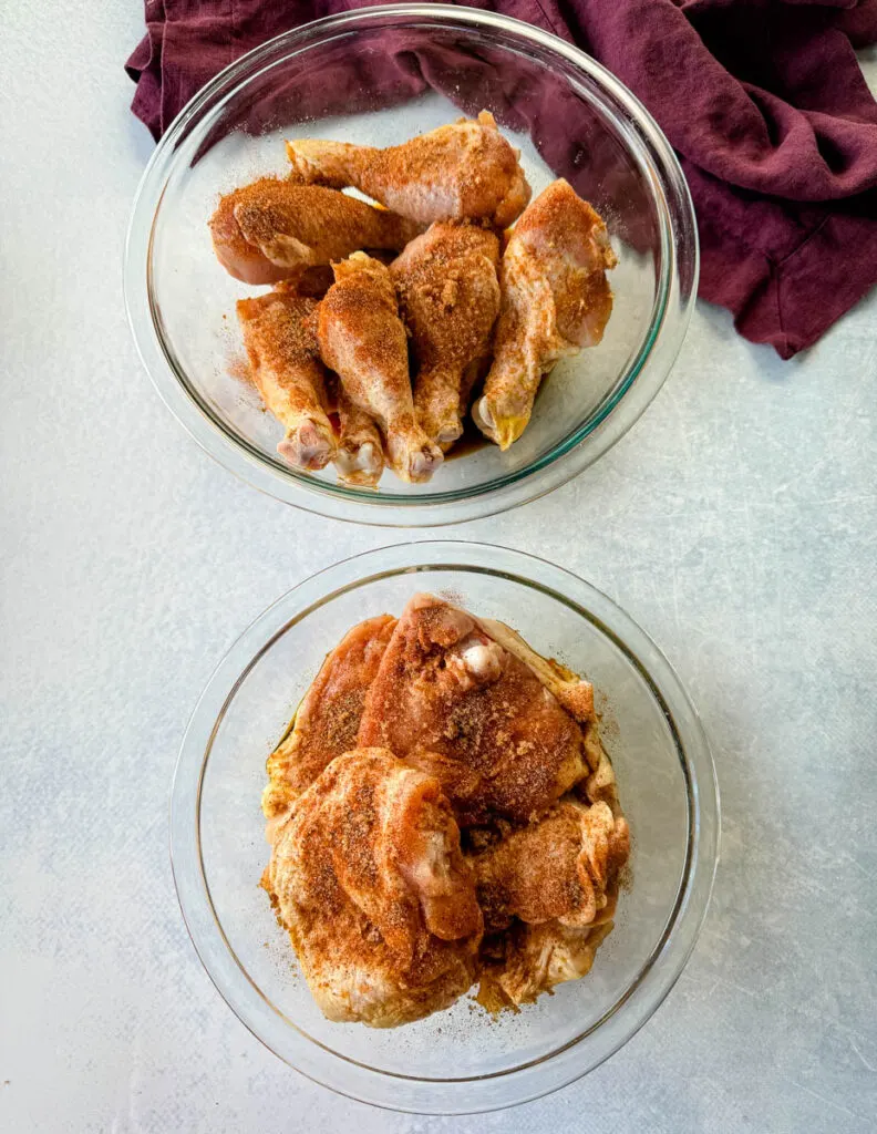 raw, seasoned marinated chicken thighs and drumsticks in glass bowls
