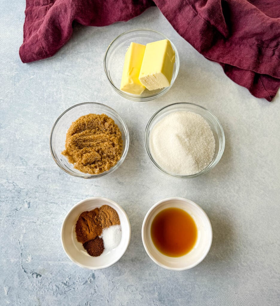 butter, brown sugar, white sugar, cinnamon, nutmeg, cloves, and vanilla extract in separate white bowls