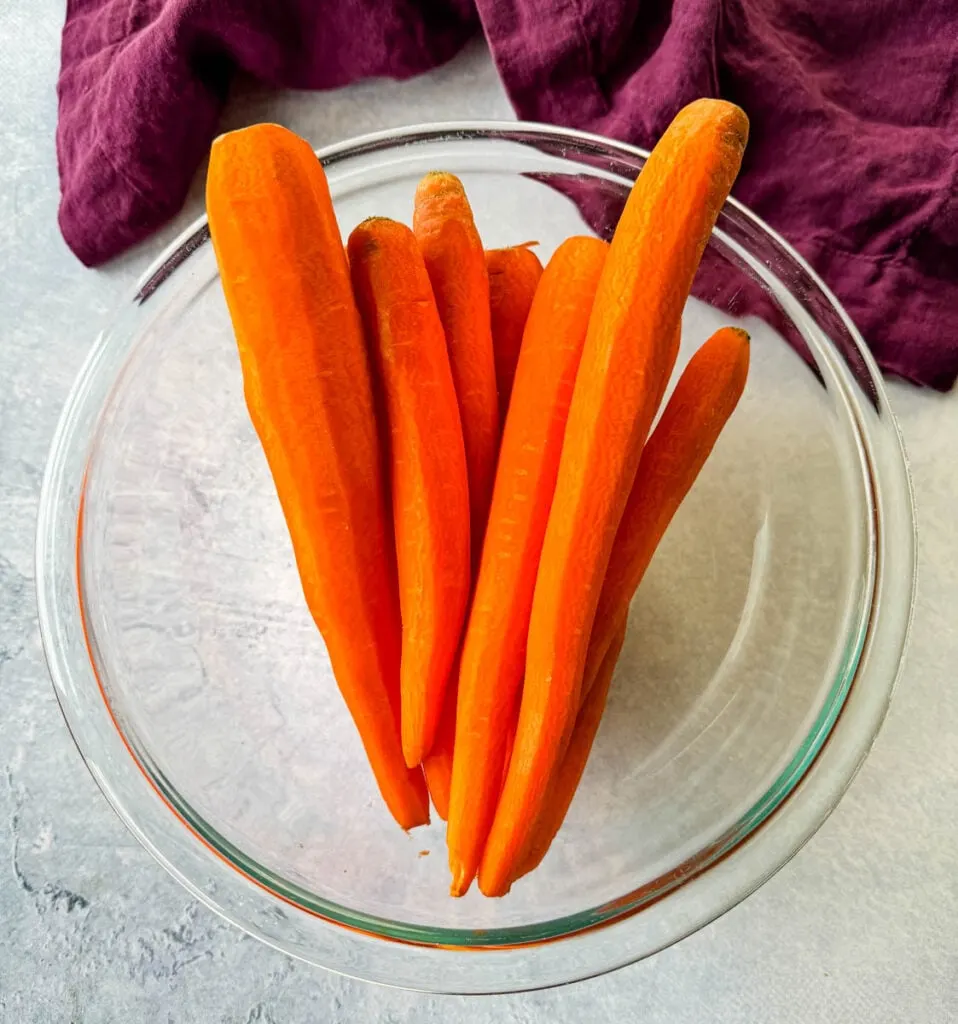 raw fresh whole carrots in a glass bowl