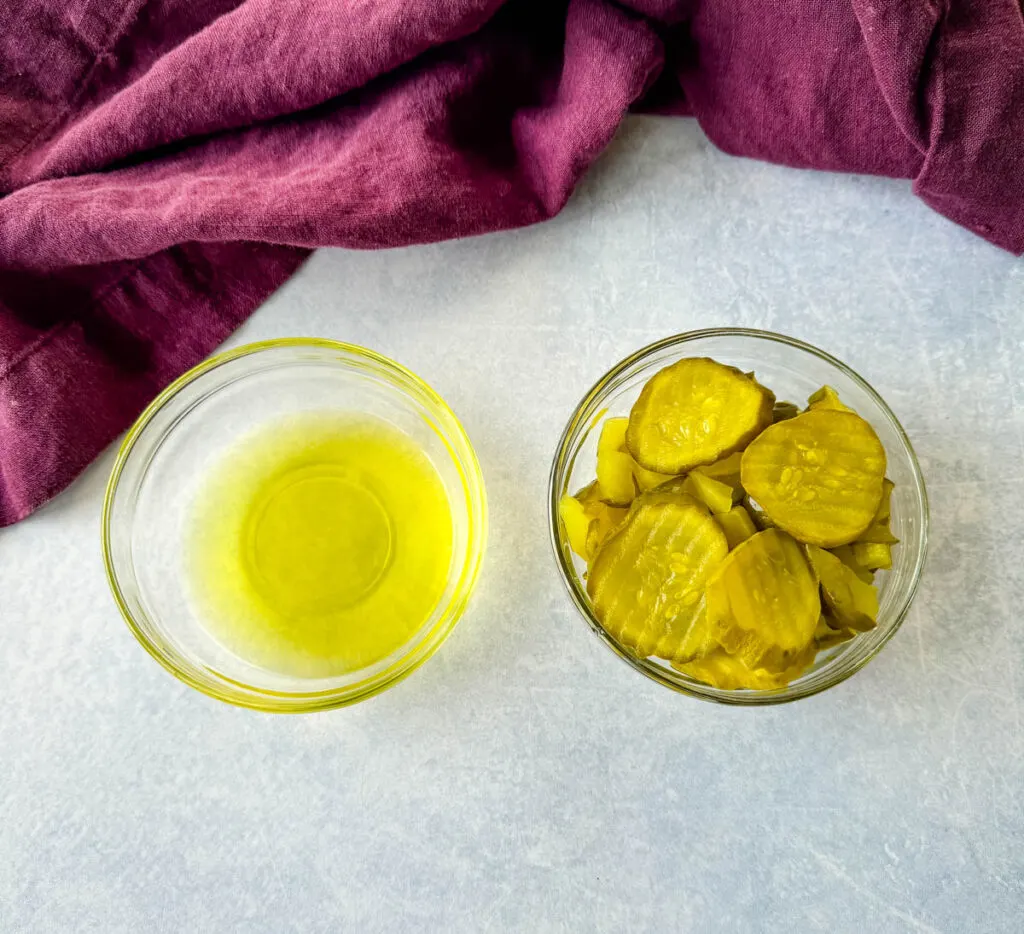 pickle juice and pickles in separate glass bowls