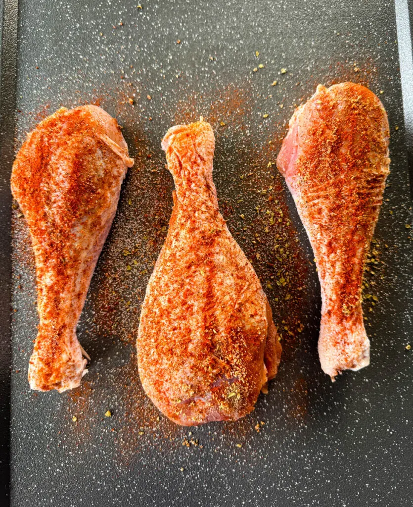 raw, seasoned turkey legs on a sheet pan