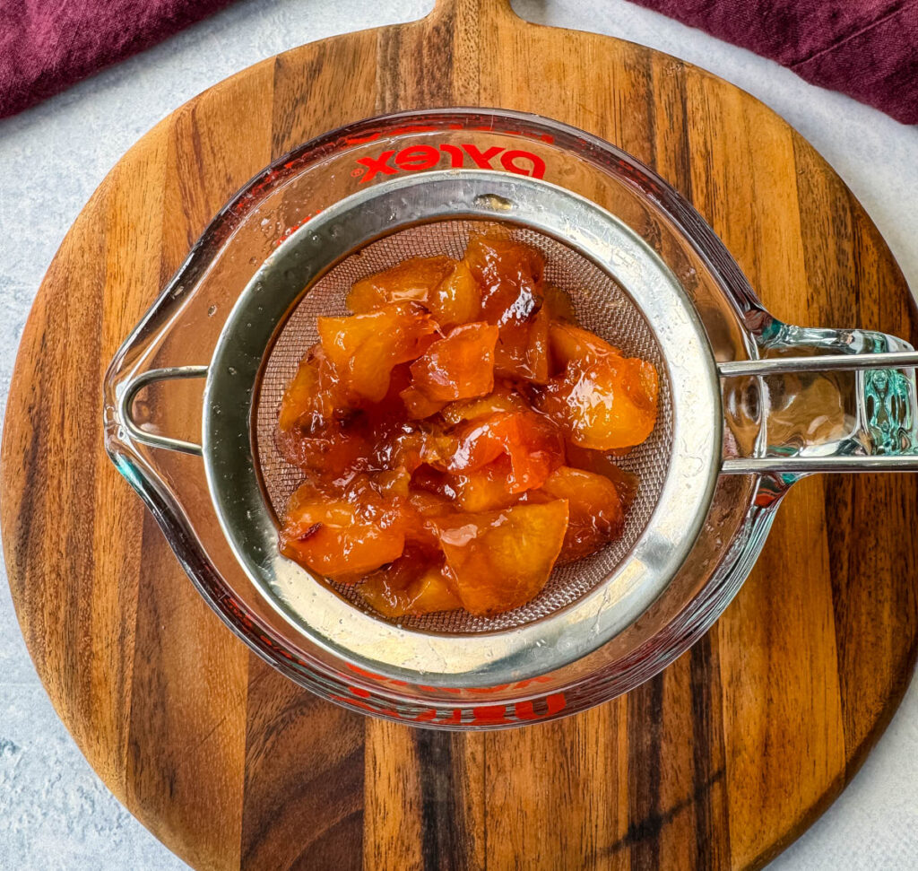 pureed peaches and simple syrup in a strainer