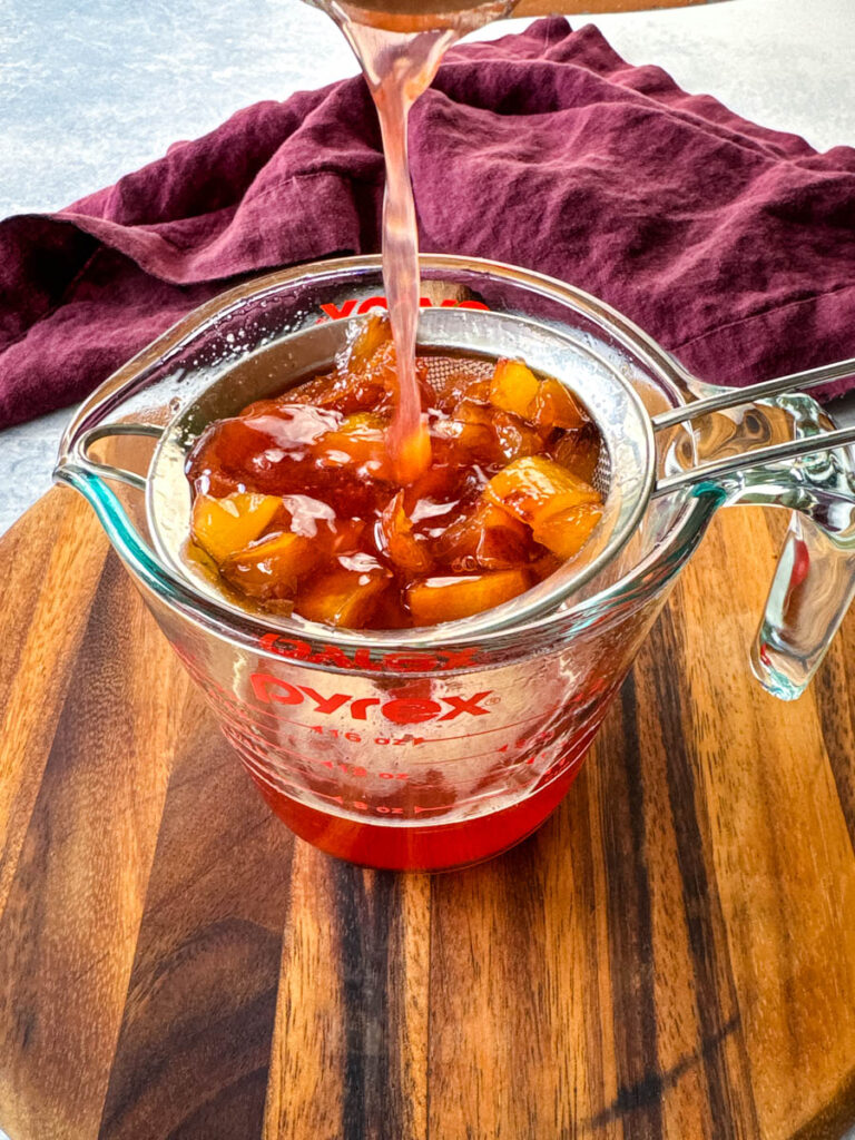 pureed peaches and simple syrup in a strainer and glass bowl