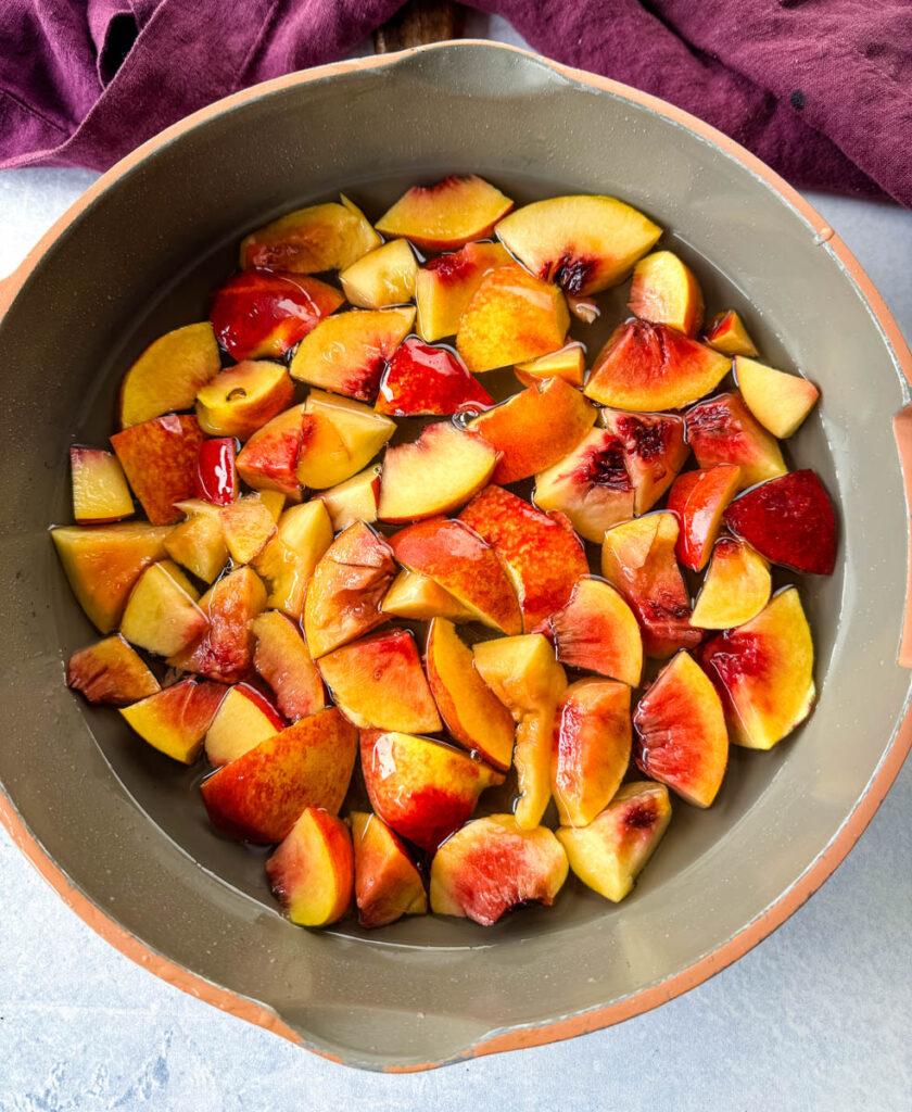 fresh sliced peaches and simple syrup in a skillet