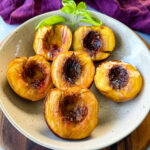 smoked peaches in a tan bowl with whipped cream and drizzled with honey