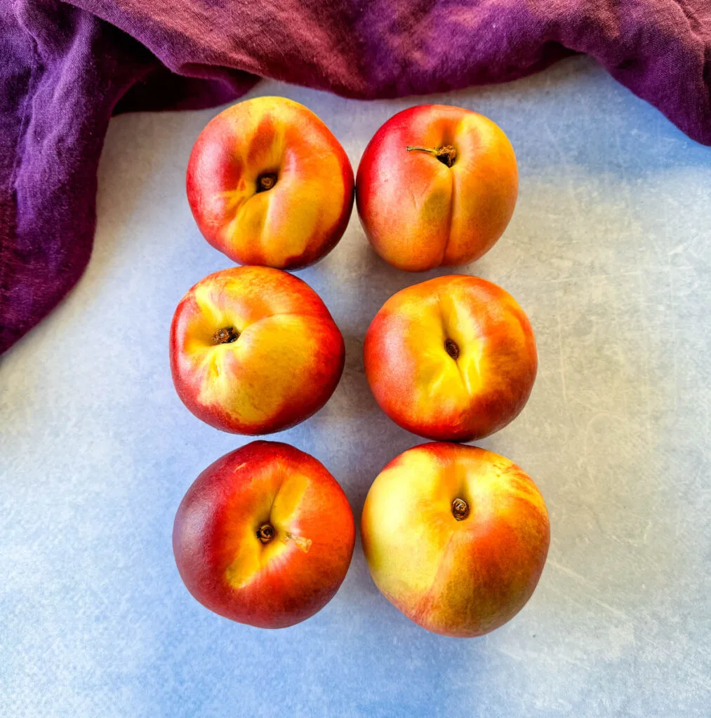 6 fresh peaches on a flat surface