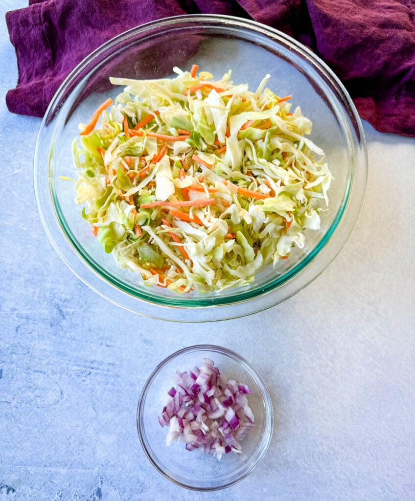 shredded cabbage coleslaw mix and diced onions in separate glass bowls