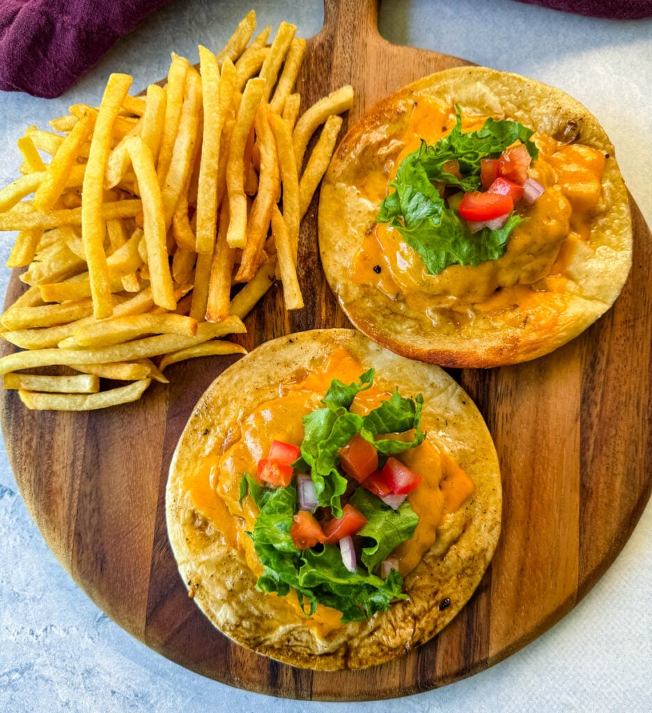 cheeseburger tacos with tomatoes, lettuce, and burger sauce on a plate with fries