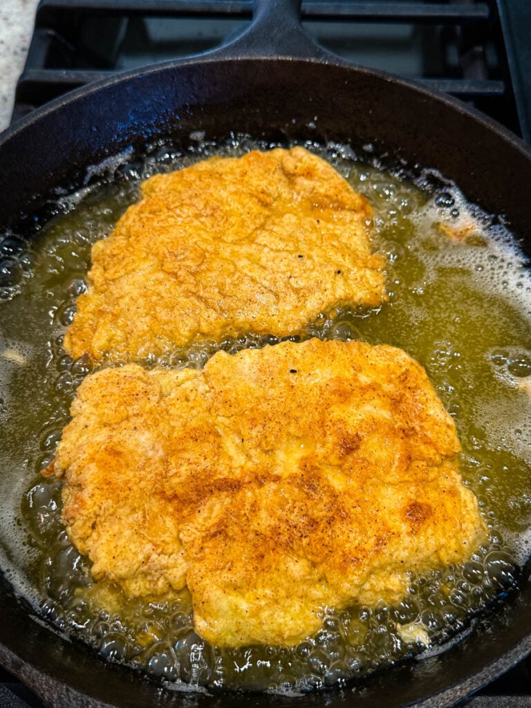 chicken fried chicken in a cast iron skillet with oil