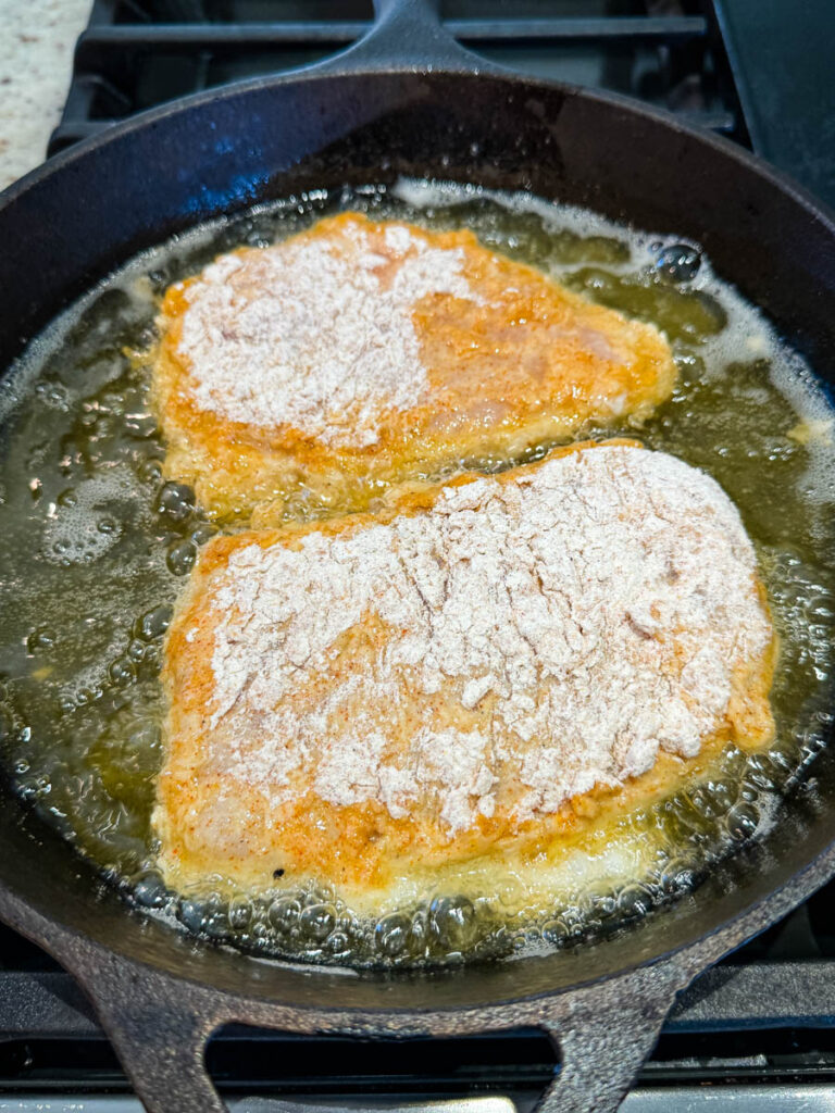 uncooked chicken fried chicken in a cast iron skillet with oil