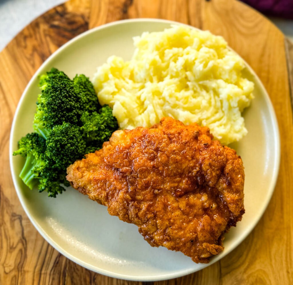 chicken fried chicken, mashed potatoes, and broccoli on a plate