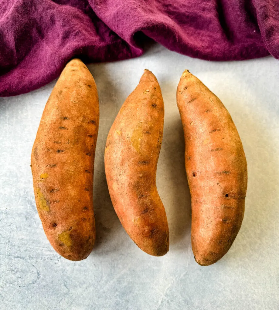 raw sweet potatoes in skin on a flat surface