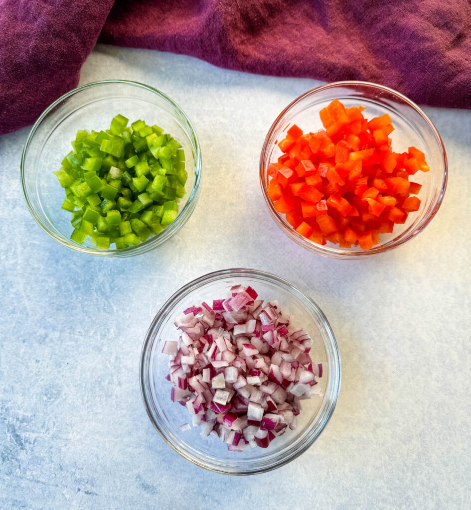 diced green peppers, diced red peppers, and diced onions in separate glass bowls