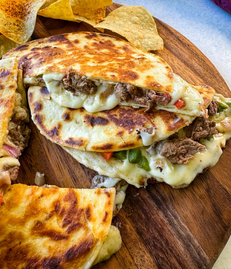 Philadelphia cheesesteak on a flat surface with chips