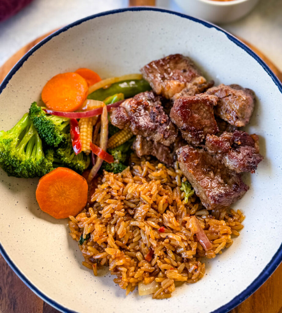 hibachi steak, vegetables, and fried rice in a white bowl