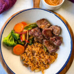 hibachi steak, vegetables, and fried rice in a white bowl