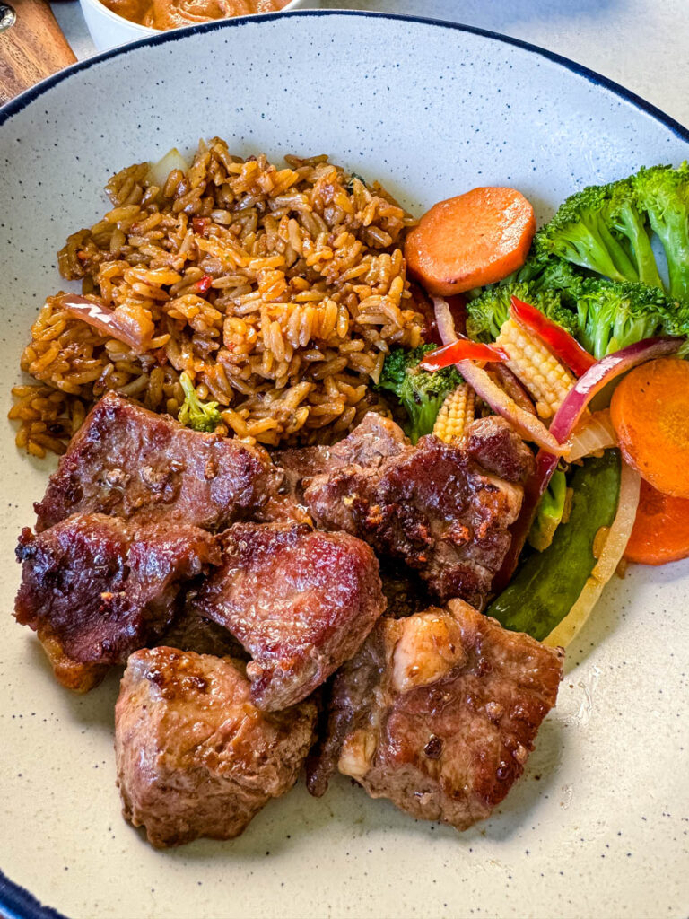 hibachi steak, vegetables, and fried rice in a white bowl