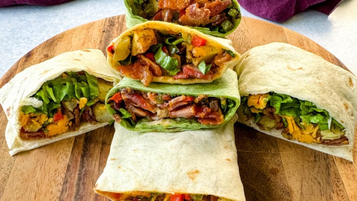 breakfast burritos with bacon, potatoes, bell peppers and cheese on a flat surface
