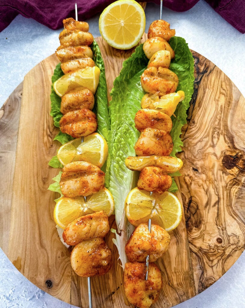 smoked scallops on skewers on a bed of lettuce with lemons