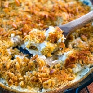 million dollar chicken casserole in a cast iron skillet with a wooden spoon