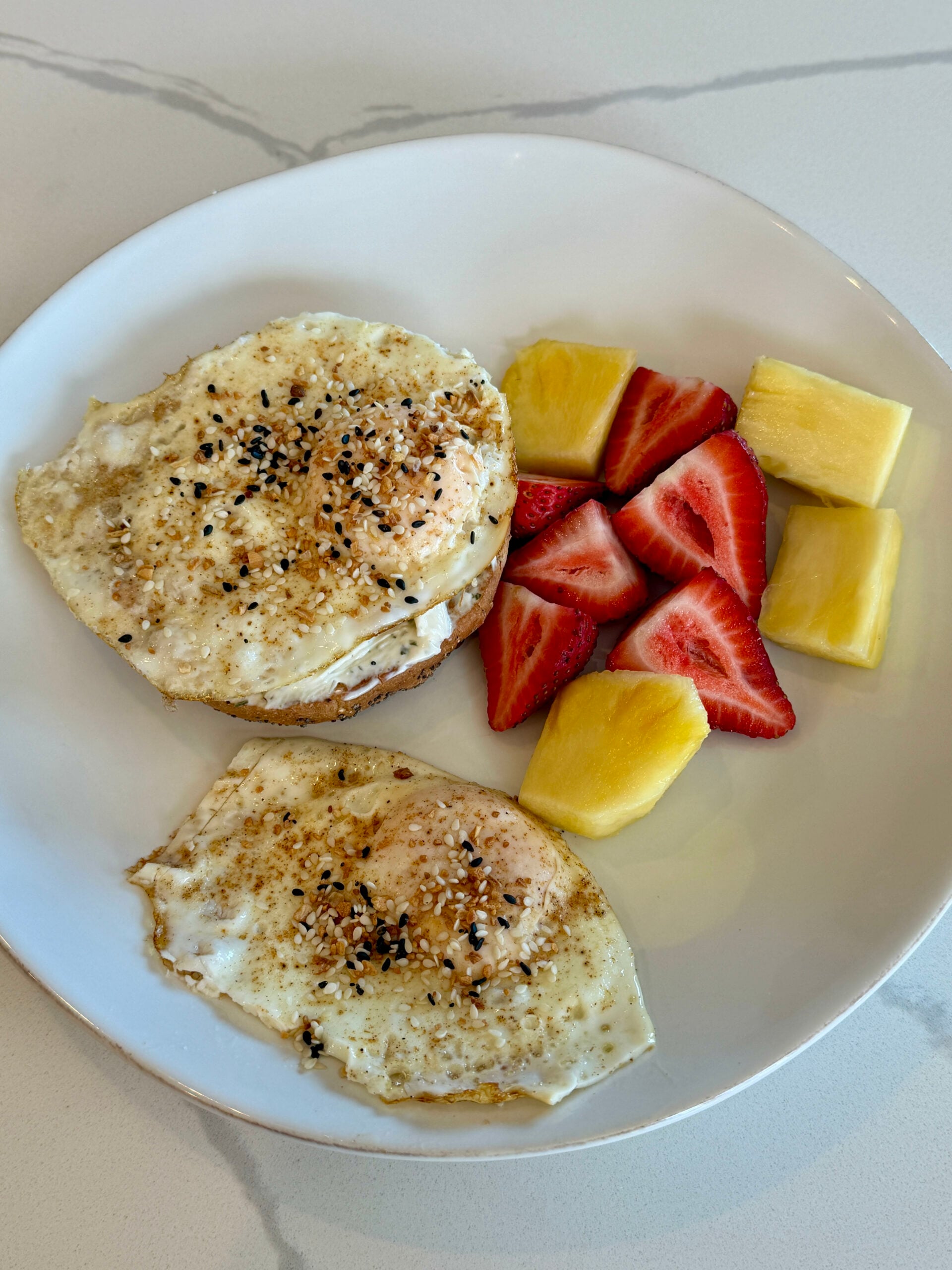 bagel, eggs, and fruit on a plate