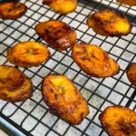 Fried sweet plantains cooling on a wire rack with crispy edges and caramelized surface