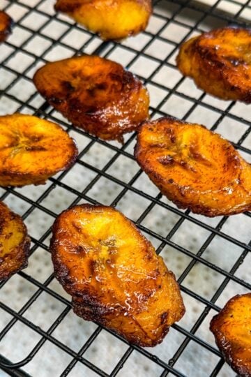 Fried sweet plantains cooling on a wire rack with crispy edges and caramelized surface