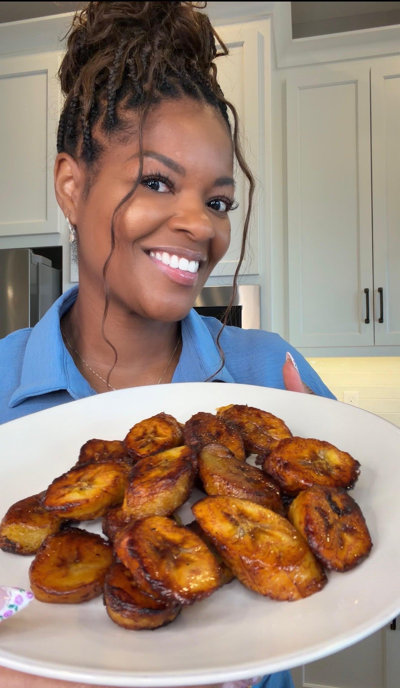 person holding a white plate of fried plantains