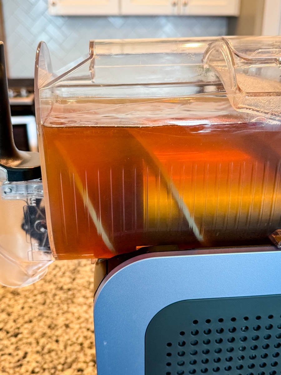 The Ninja Slushi machine filled with iced tea, with the internal paddles visible through the clear container.