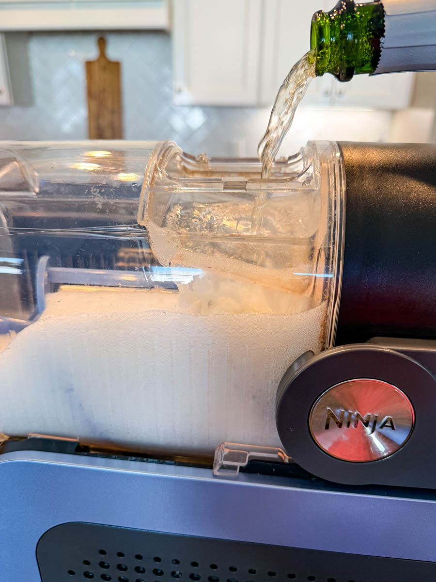 Champagne being poured into the Ninja Slushi machine’s frozen chamber.