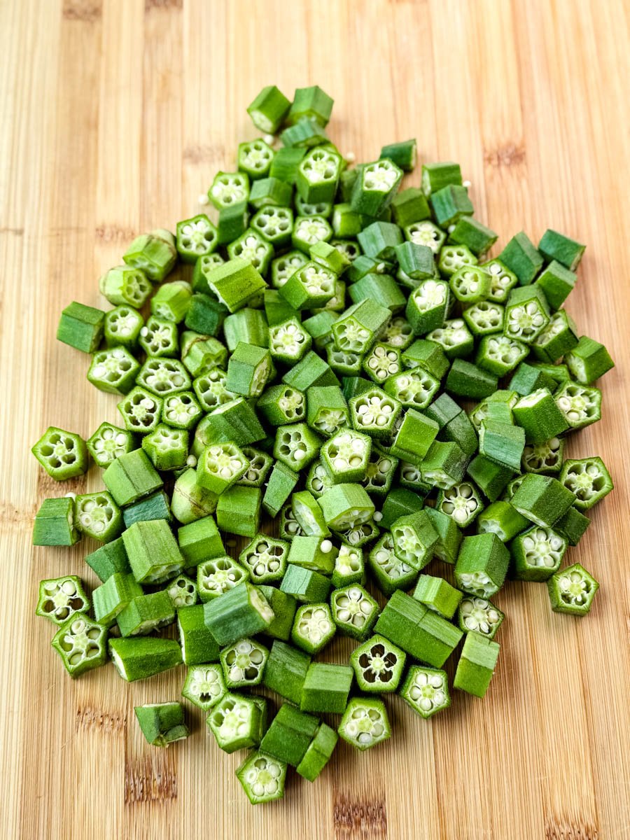 Freshly chopped raw okra on a wooden cutting board.