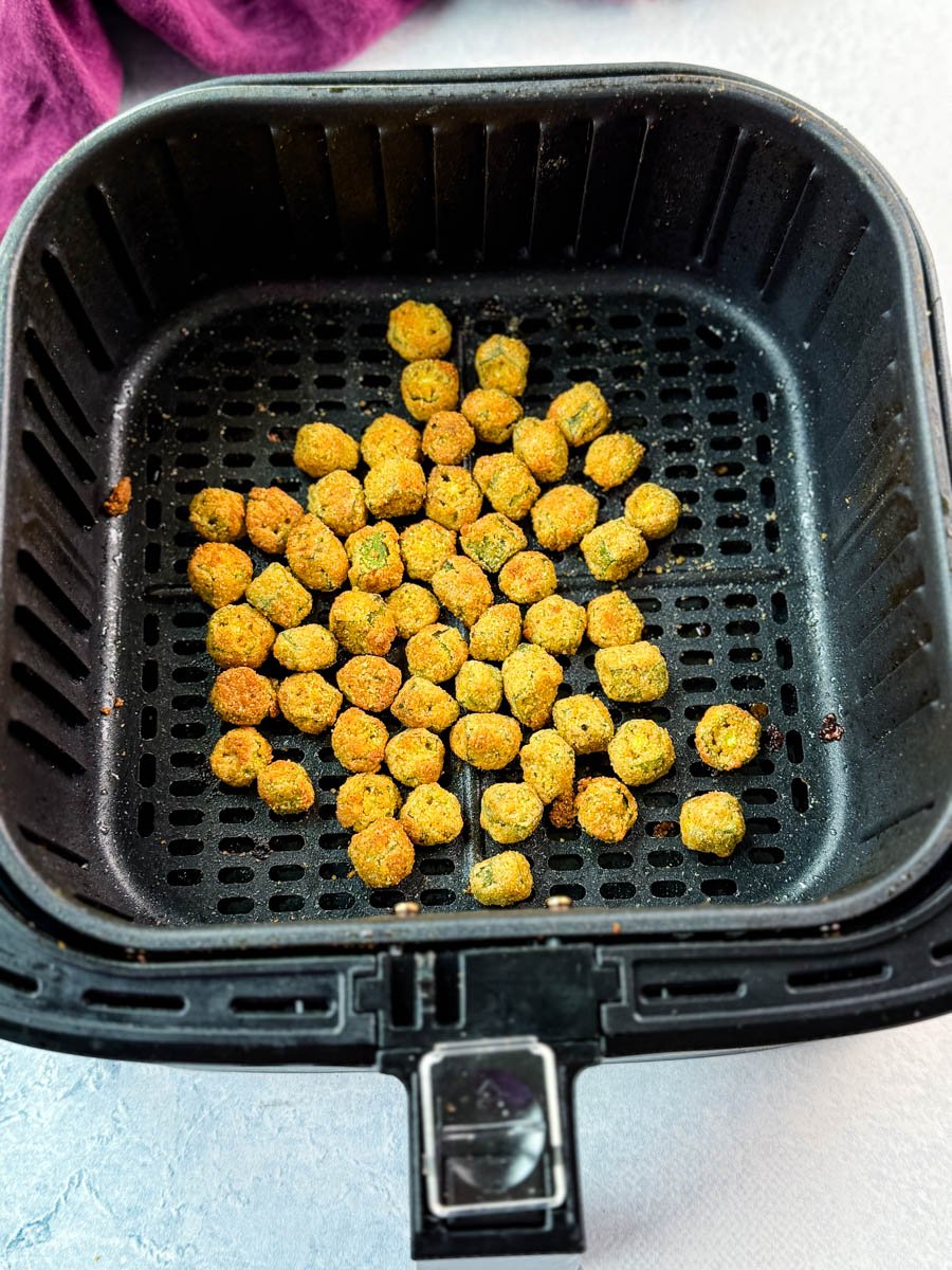 Air fryer with golden brown breaded okra inside after cooking.