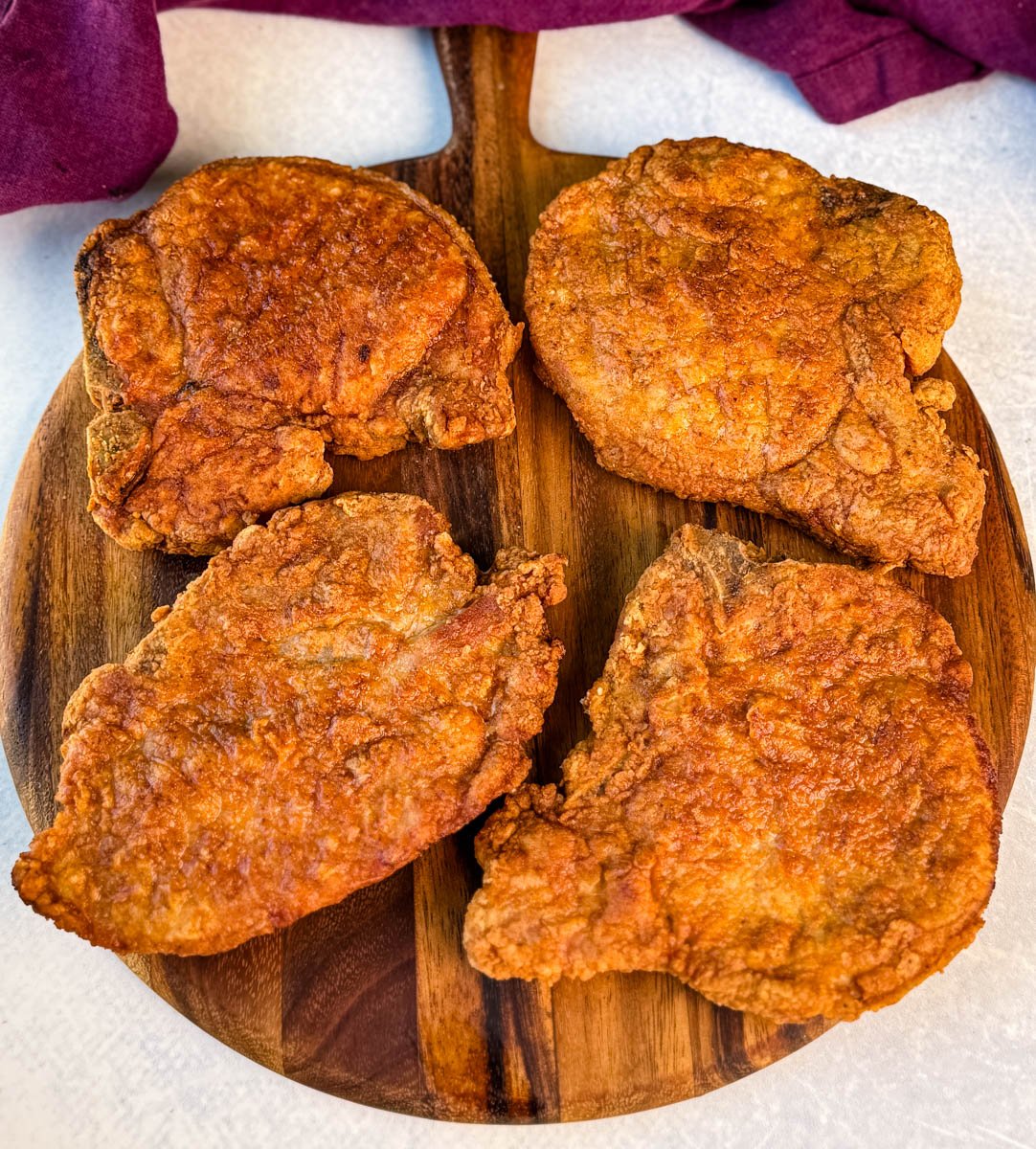 Close-up of golden fried pork chops with a crunchy coating arranged on a cutting board.
