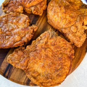 Close-up of golden fried pork chops with a crunchy coating arranged on a cutting board.