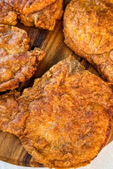 Close-up of golden fried pork chops with a crunchy coating arranged on a cutting board.