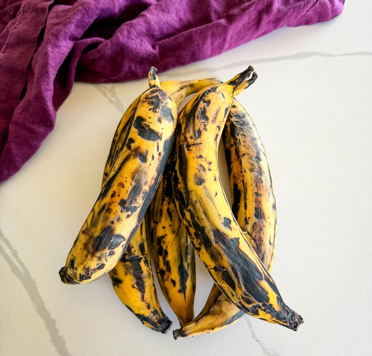 Ripe plantains with black and yellow skins showing they are ready for frying