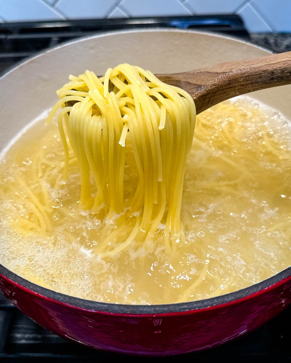 cooked spaghetti noodles boiling in a red Dutch oven