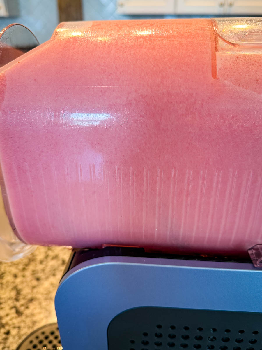 Another angle of the blended pink slush inside the Ninja Slushi machine, showing the fluffy texture against the container walls.