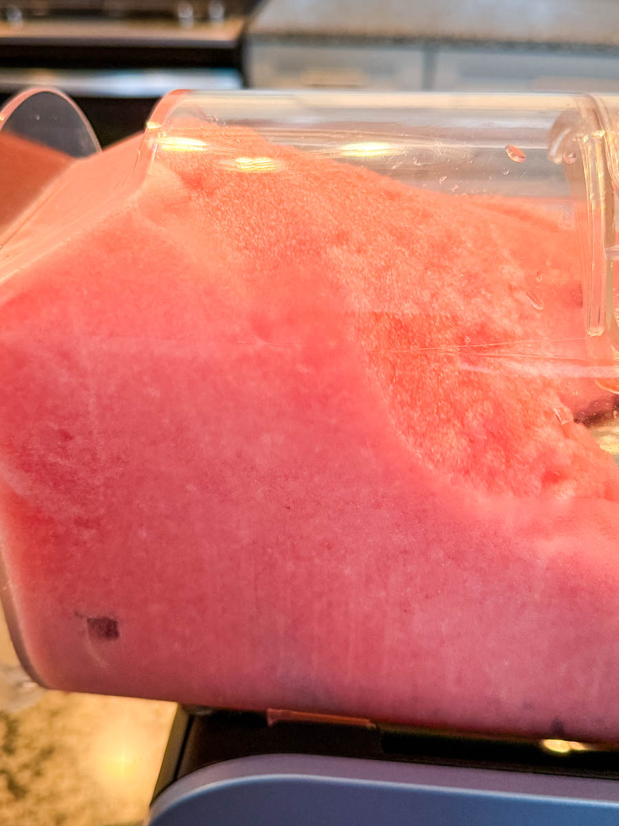 The Ninja Slushi machine after blending, showing the smooth pink slush forming inside the container.