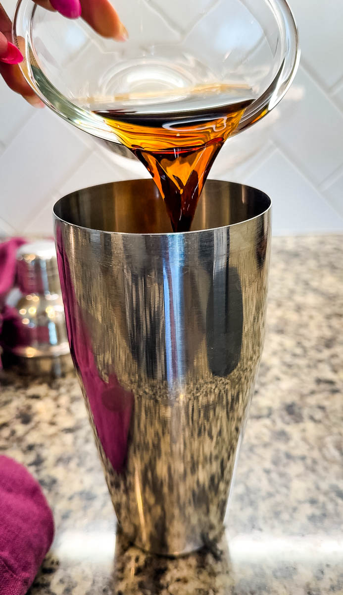 Close-up of coffee being poured into a stainless steel cocktail shaker.