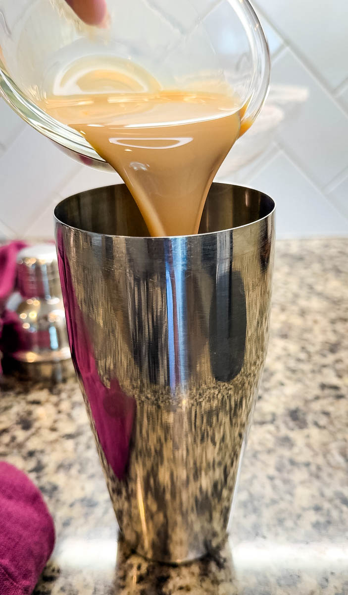 Close-up of Kahlúa being poured into a stainless steel cocktail shaker.