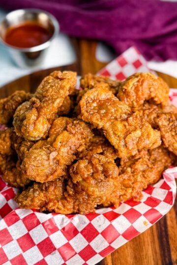 Overhead view of a basket of fried chicken gizzards with dipping sauce in the background.