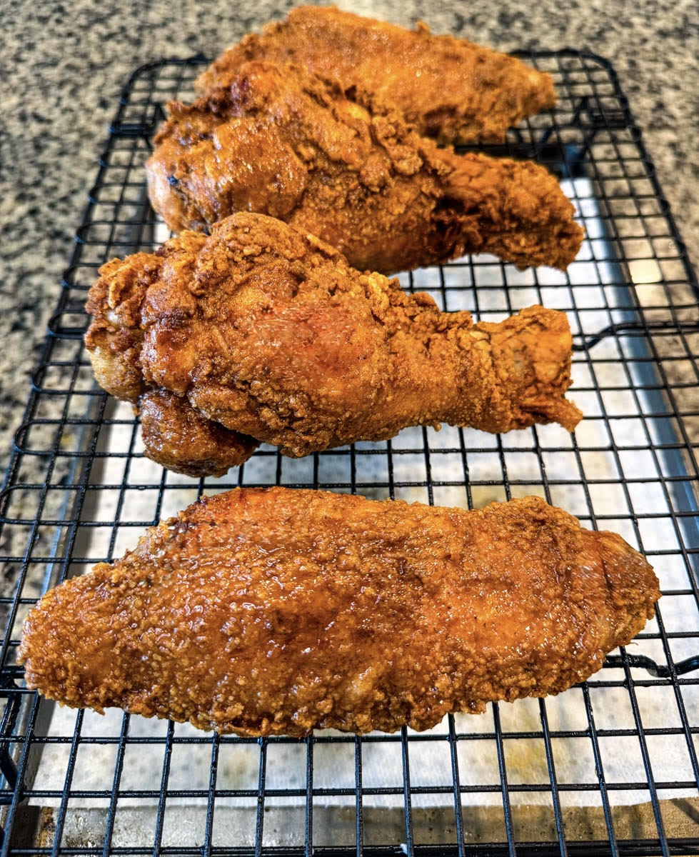 Side view of crispy fried turkey wings on a wire rack lined with paper towels to absorb excess oil.