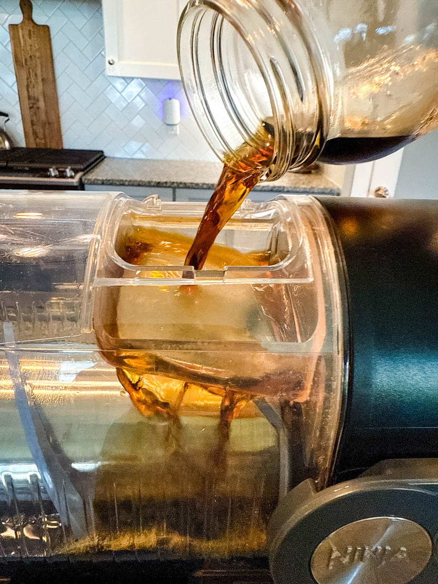 Coffee mixture being poured from a mason jar into the Ninja Slushi machine.