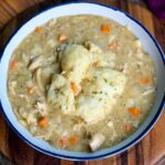 Bowl of chicken and dumplings – A close-up of a white bowl filled with creamy chicken and dumplings, featuring tender shredded chicken, chunks of carrots, and fluffy biscuit dumplings on top.